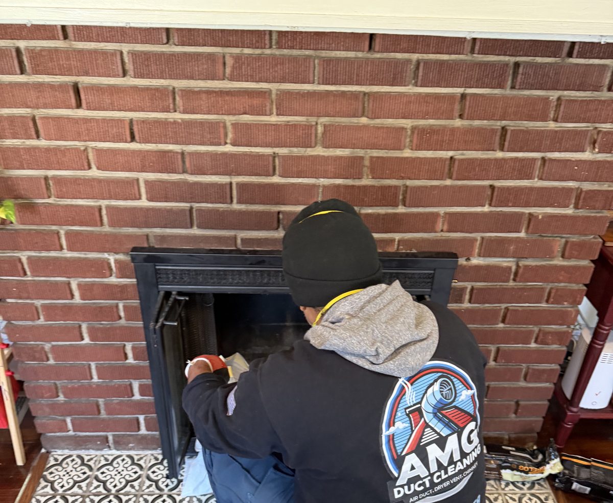 An AMG technician at work inside a brick fireplace