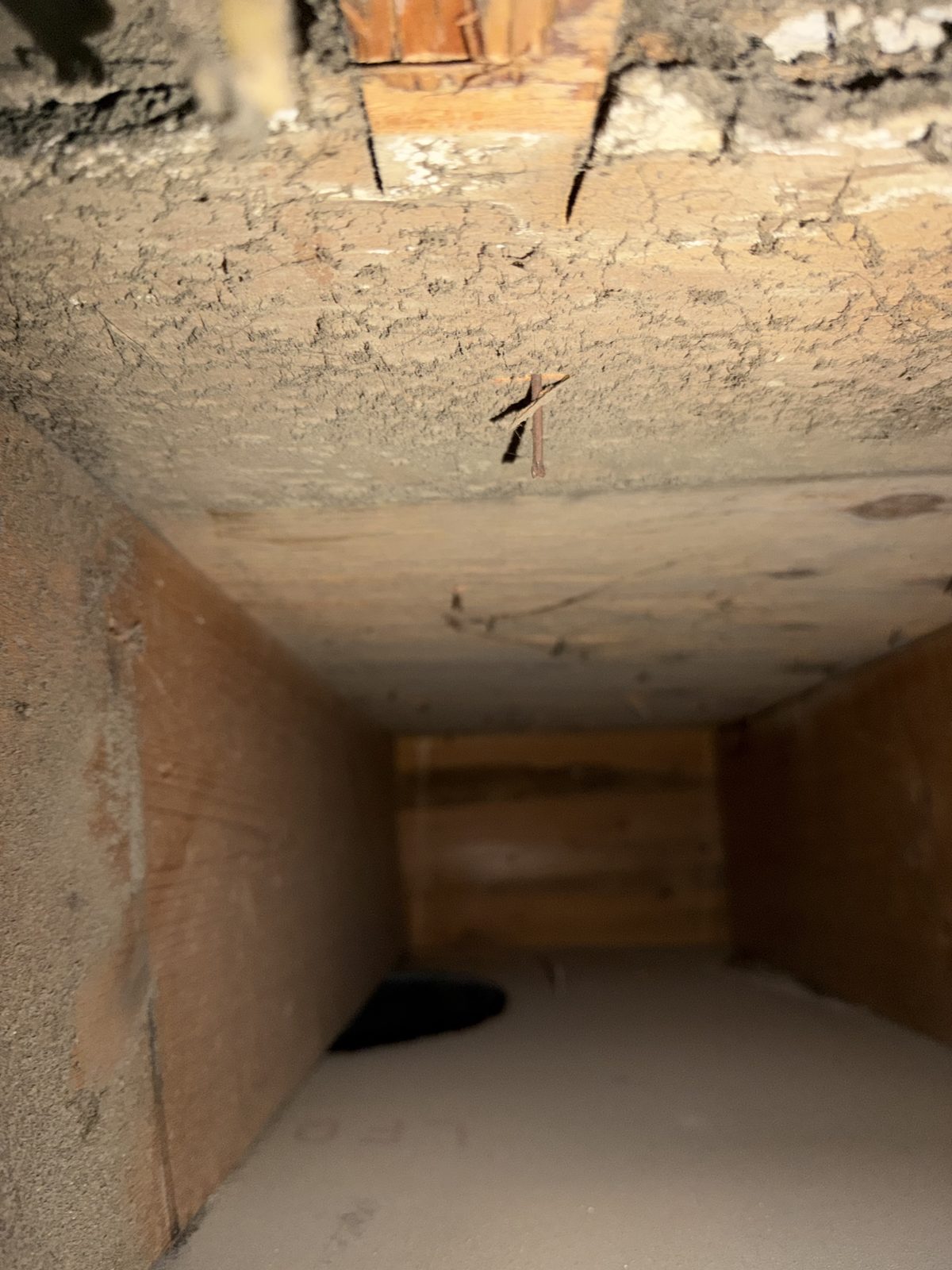 Dust caked on the wood inside a joist cavity used as a duct