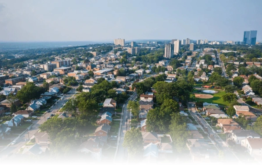 Aerial view of a suburban neighborhood of Bergin, NJ with tree-lined streets and high-rise buildings in the background.