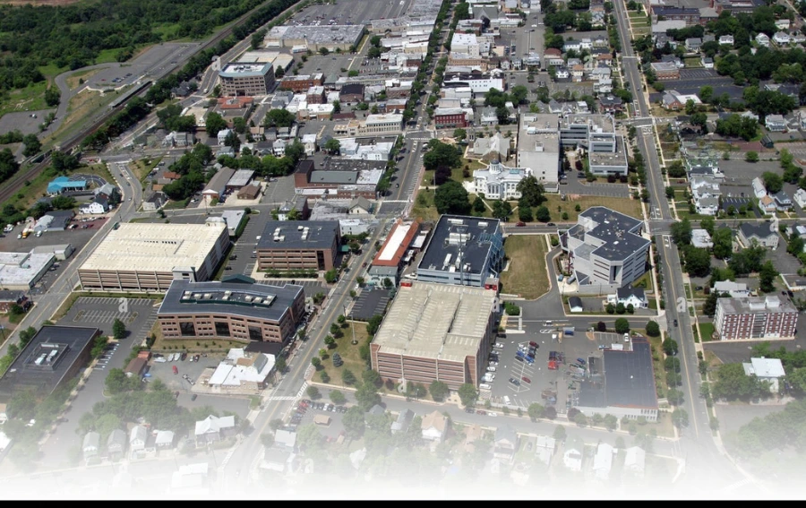 An aerial view of a cityscape in Somerset County, NJ, showcasing a mix of commercial and residential buildings, roads, and greenery